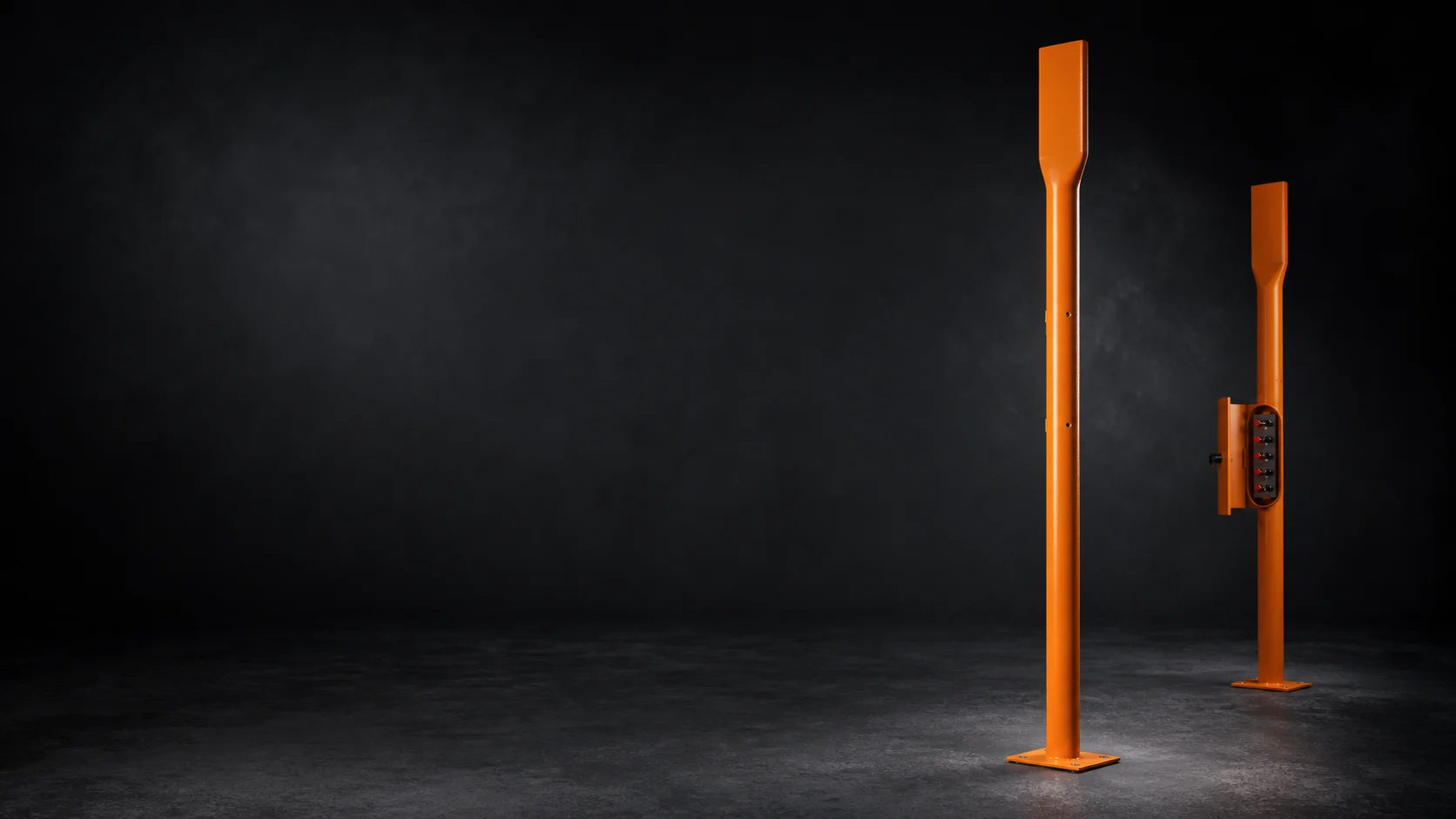 Two slender orange cathodic protection test posts on a dark studio background